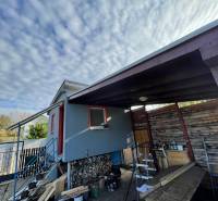 A cottage in Komárno in Nová Osada with a staircase and a wooden shelter under the clouds.