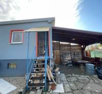 A cottage in Komárno on Nová Osada Street with a covered terrace and wooden staircase.