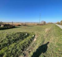 The landscape around the cottage on Nová osada street in Komárno with a field and a road.