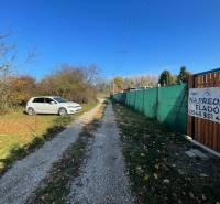The path to the cottage in Nova Osada in Komárno, next to a parked white car.