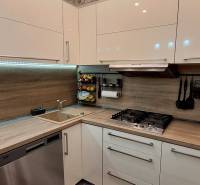 A kitchen in a 3-room apartment with a kitchen unit, extractor hood, appliances, and a floor with a wooden decor.