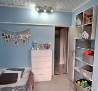 Children's room in a 3-room apartment with blue walls, shelves, and light furniture.