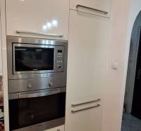 A kitchen in a 3-room apartment with white cabinets and built-in appliances.
