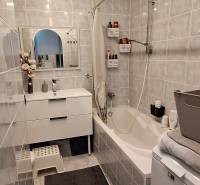A bathroom with light tiles, a bathtub, a sink, and a mirror in a 3-room apartment.