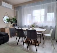 Living room with a gray sofa, wood-decor table, and light curtains in a 3-room apartment.