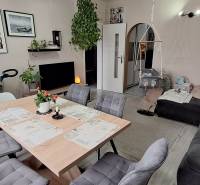 Living room of a three-room apartment with a sofa, table, chairs, and a children's swing.