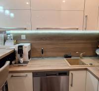 A kitchen in a 3-room apartment with a wooden decor floor, equipped with appliances and a bar counter.