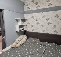 Bedroom in a 3-room apartment with a floral pattern on the wallpaper and gray walls.
