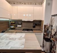 A kitchen in a 3-room apartment with a wooden decor floor, modern appliances.