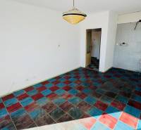 A room in a one-room apartment with a colorful tiled floor and a pendant light.