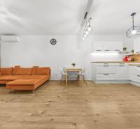 Living room in a 2-room apartment with an orange sofa and a wooden-patterned floor.