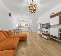 Living room with an orange sofa and a wooden decor floor in a two-room apartment.