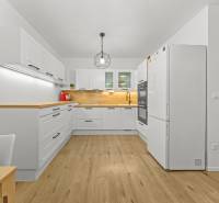 A kitchen in a 2-room apartment with white cabinets and a wood-patterned floor.