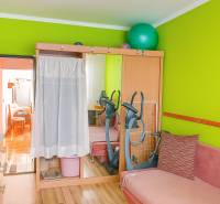 A striking green wall and a mirrored wardrobe in a 2-room apartment. In the background, a stationary bike.