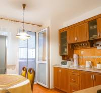 A kitchen in a 2-room apartment with wooden cabinets, a dining table, and access to a balcony.