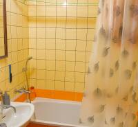 Bathroom in a 2-room apartment with a bathtub, shower curtain, and tiles.