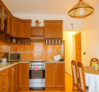 A kitchen in a 2-room apartment with wooden cabinets and a dining table.