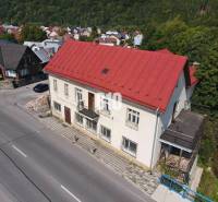 A building in Belá with a red roof, surrounding houses and nature.