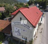 The building of the inn in Belá with a red roof and a depiction on the wall.