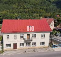 A building in Belej with a red roof, surrounded by greenery and a road in the foreground.
