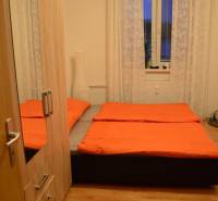 Bedroom in a two-room apartment with orange bedding and a wooden decor floor.