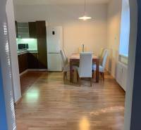 Dining area in a 2-room apartment with a wooden decor floor and four chairs.