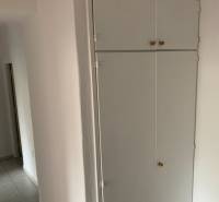 White built-in wardrobe in the hallway of a 2-room apartment with tiles.