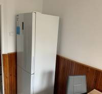 A kitchen in a 2-room apartment with a refrigerator, dark tiles, and a dining area.