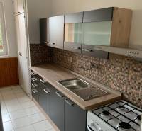 A kitchen in a 2-room apartment with mosaic tiles and a gas stove.
