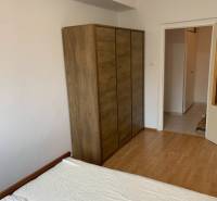 Bedroom in a 2-room apartment with a wooden decor floor and a wardrobe.