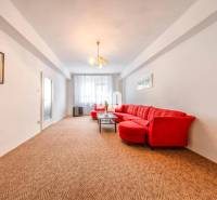 Living room with a light wall, red sofa, and carpet in a 4-room apartment.