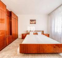 Bedroom in a 4-room apartment with a double bed and built-in wardrobes, light curtains.
