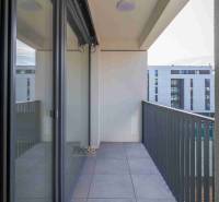 Balcony of a 2-room apartment in Poprad with tiles and a view of modern buildings.