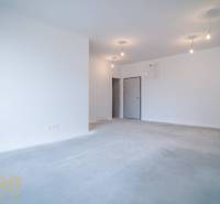 Spacious living area in a 2-room apartment, white walls, basic lighting.