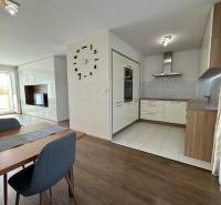 Dining area in a 4-room apartment with a wood-patterned floor and a kitchen in the background.