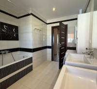 A bathroom in a 4-room apartment with two sinks, a bathtub, and tiles.