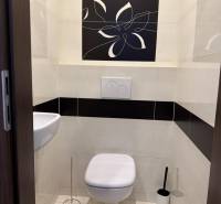 A bathroom with a wall-mounted toilet and sink in a 4-room apartment, decorated with a floral motif.