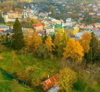 Aerial view of residential plots in Banská Štiavnica, surrounded by nature and buildings.