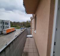 The balcony of a studio apartment on Pezinská Street in Malacky with a view of the parking lot and greenery.