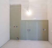 An empty room in a 3-room apartment under construction with installation connections.