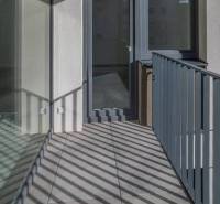 A balcony with tiles and glass railing in a 3-room apartment.