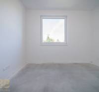 An empty room with white walls in a 3-room apartment without flooring.