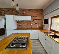 A kitchen in a family house with a brick wall, wooden accessories, and a floor with a wood decor.