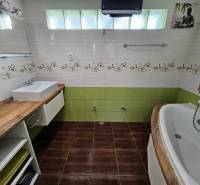Bathroom in a family house with a wooden decor floor, sink, and bathtub.