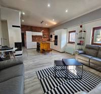 Living room with kitchen in a family house, floor with wood decor, brick wall.