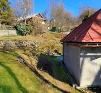 A garden in Štiavnické Bane with a view of the family house and the surrounding landscape.