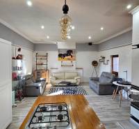 Living room in a family house with sofas, kitchen, and wooden decor flooring.