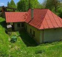 A family house on the street in Štiavnické Bane with a red roof and a grassy garden.