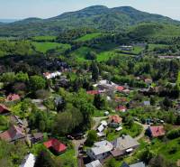 A view of family houses in Štiavnické Bane surrounded by greenery and hills.
