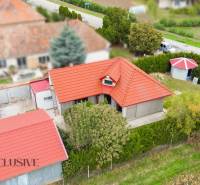 A family house in Bátorove Kosihy, red roof, green surroundings, adjacent buildings.